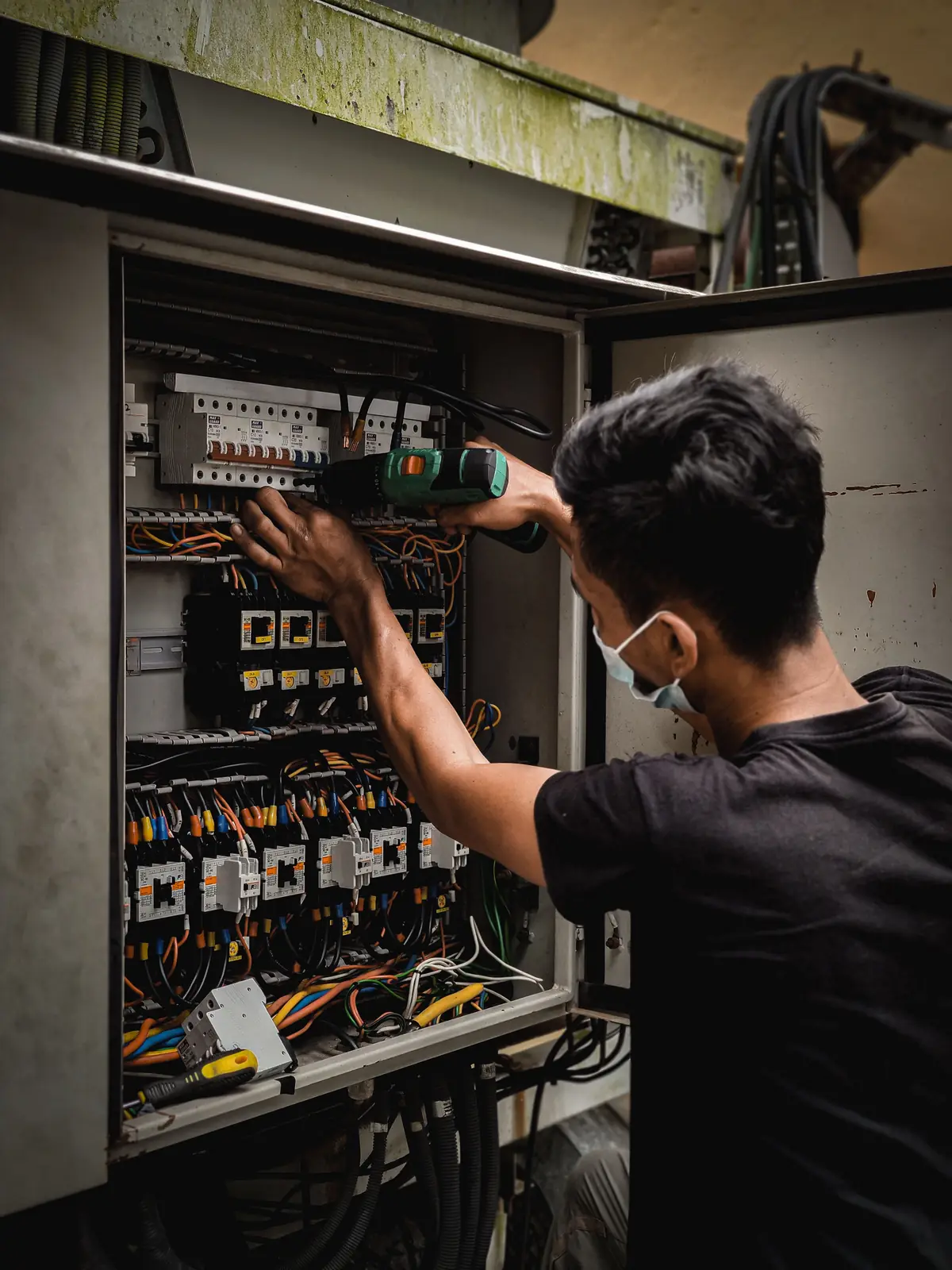 An electrician working inside a large distribution board, for commercial electrical in Abbotsford